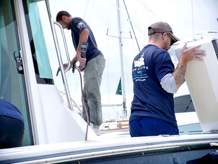 Two marine repair technicians working on a yacht.